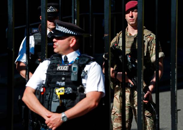 British army soldier from the Parachute Regiment stands alongside a police officer behind the gates to Downing Street, the official residence of Britain's Prime Minister, in central London on May 26 after Operation Temperer was put into force placing soldiers under police command on British streets in response to the May 22 terror attack at the Manchester Arena. Britain is hunting for a Libya-linked jihadist network thought to be behind the May 22 bombing at an Ariana Grande concert in Manchester, as US President Donald Trump threatened to prosecute anyone leaking details from the investigation to US media. / AFP PHOTO / Adrian DENNIS — frame 5/5 (612×437)