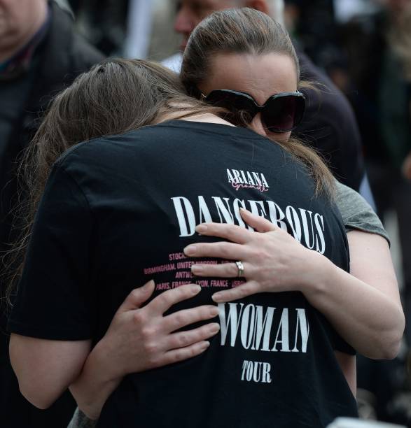 Woman hugs a girl, wearing a t-shirt from Ariana Grande's Dangerous Woman near floral tributes in Albert Square in Manchester, northwest England on May 24 following the May 22 terror attack at the Manchester Arena. Police on Tuesday named Salman Abedi -- reportedly British-born of Libyan descent -- as the suspect behind a suicide bombing that ripped into young fans at an Ariana Grande concert at the Manchester Arena on May 22, as the Islamic State group claimed responsibility for the carnage. / AFP PHOTO / CHRIS J RATCLIFFE — frame 1/3 (587×612)