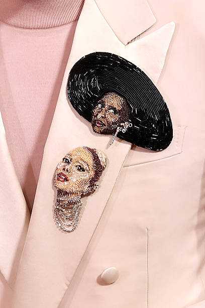 Jon M. Chu wears brooches with Ariana Grande and Cynthia Erivo's "Wicked" character likenesses during the 83rd annual Go